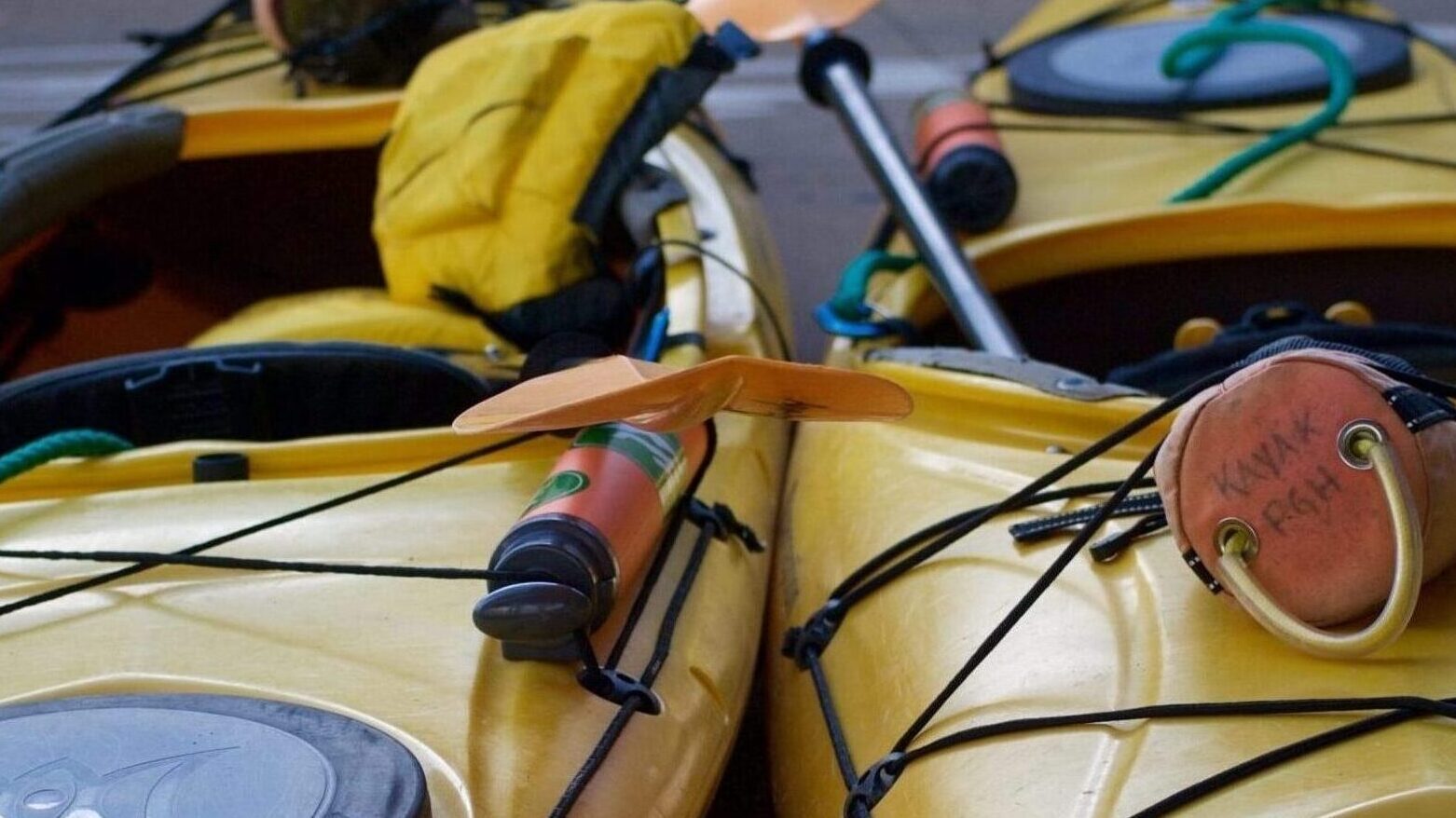 Two yellow kayaks fitted with various rescue gear including a bilge pump and throw bag.
